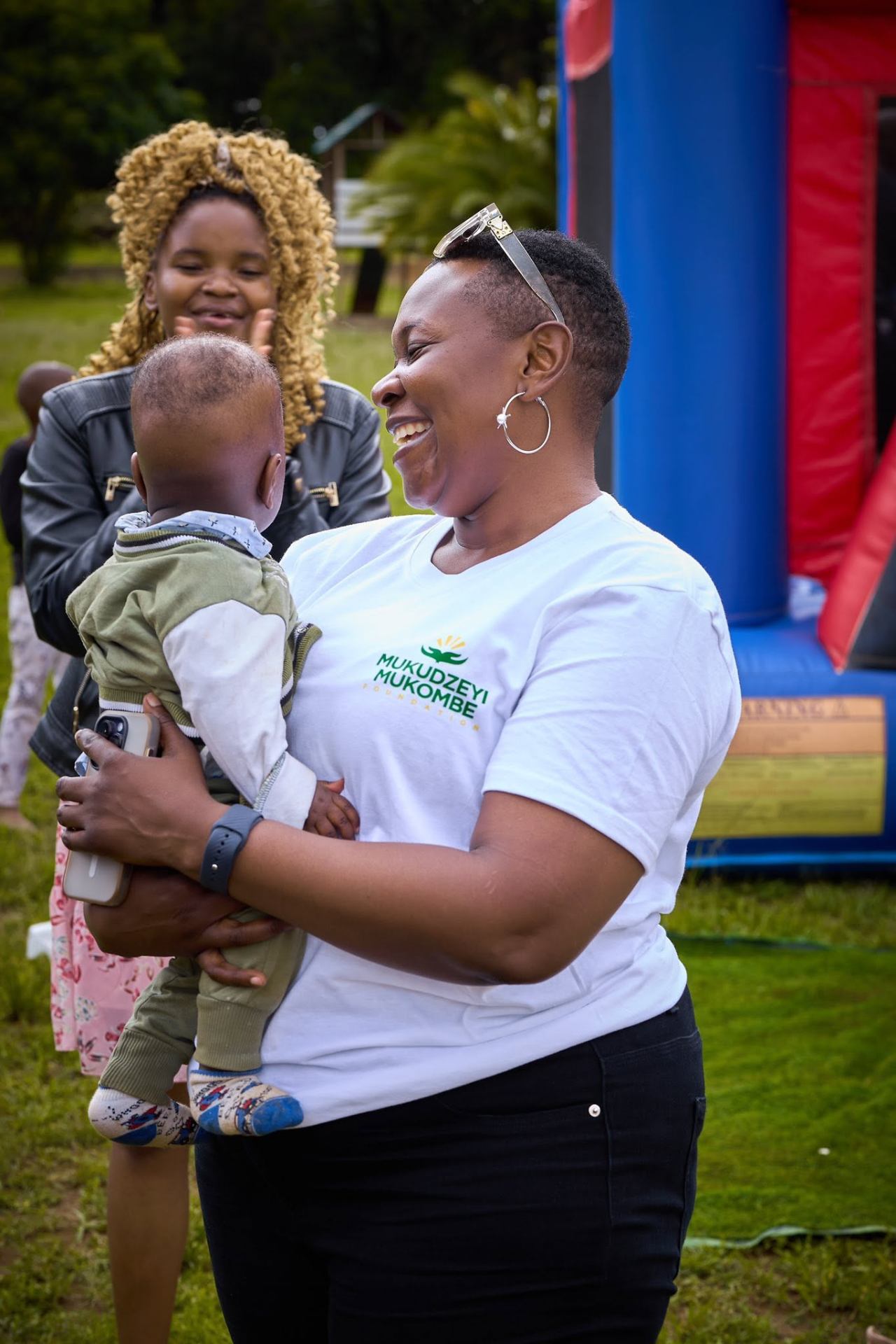 A volunteer sharing a joyful moment with a mother and child
